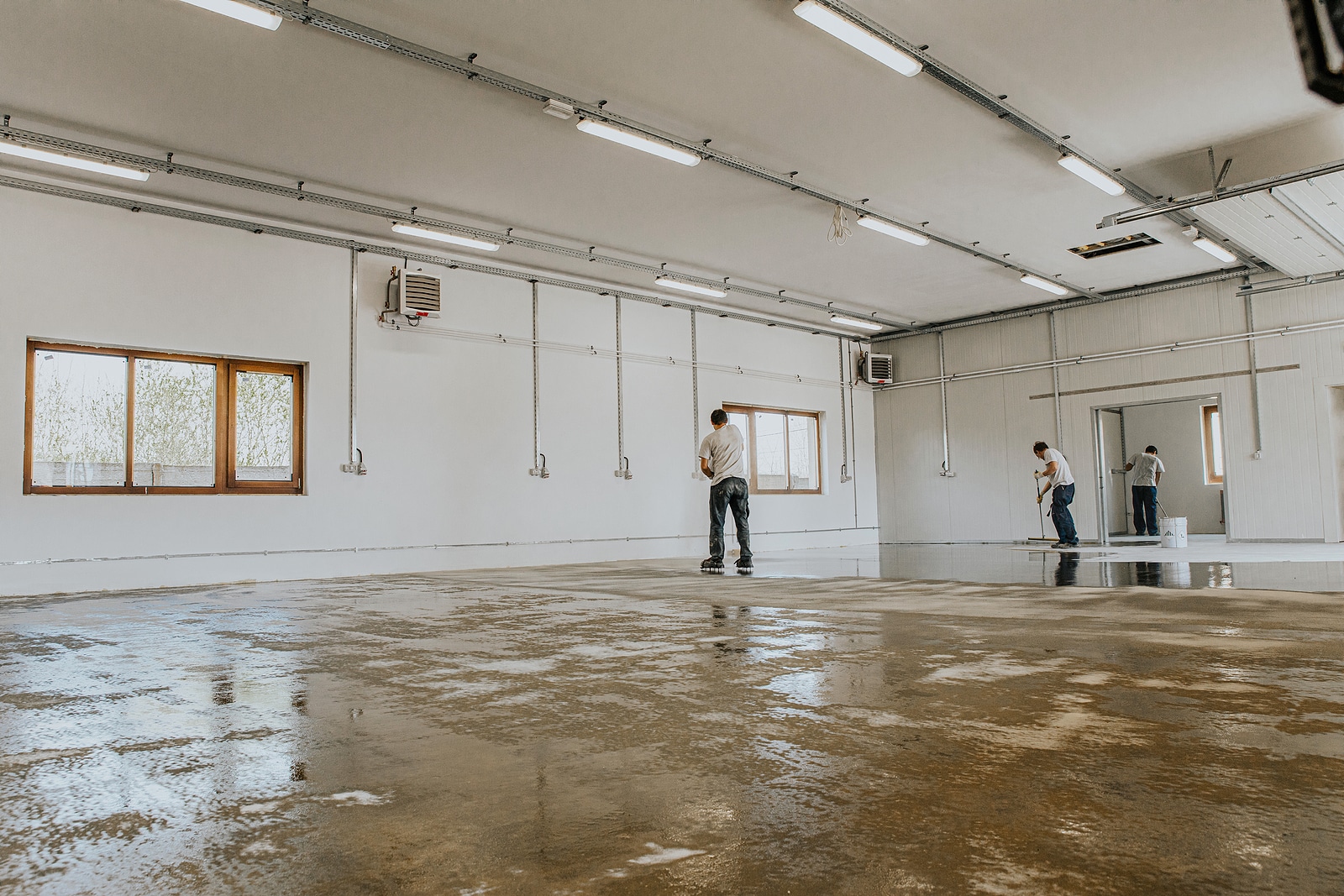 Construction workers applying epoxy resin in an industrial hall