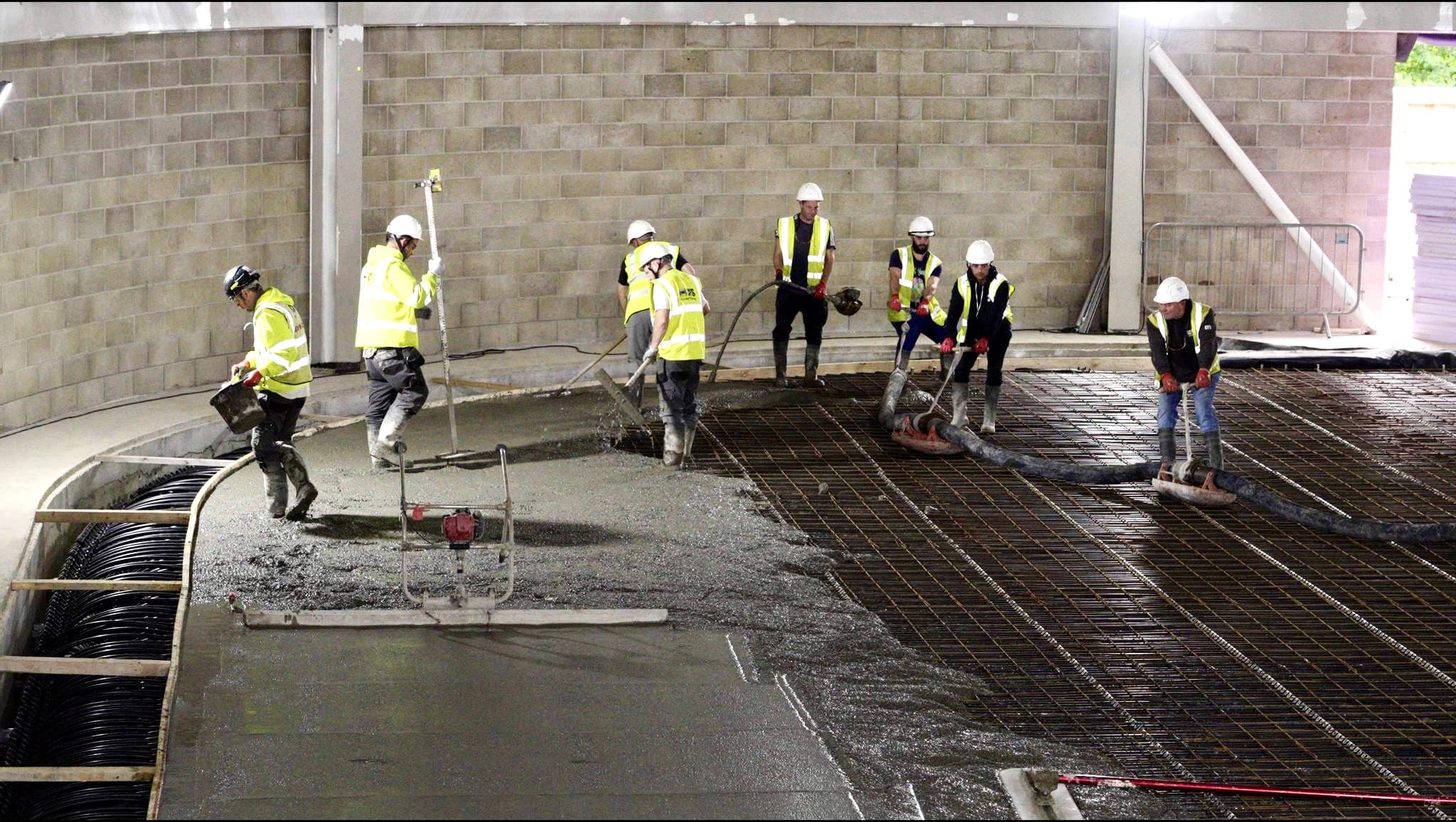 Team of workman pouring concrete floor