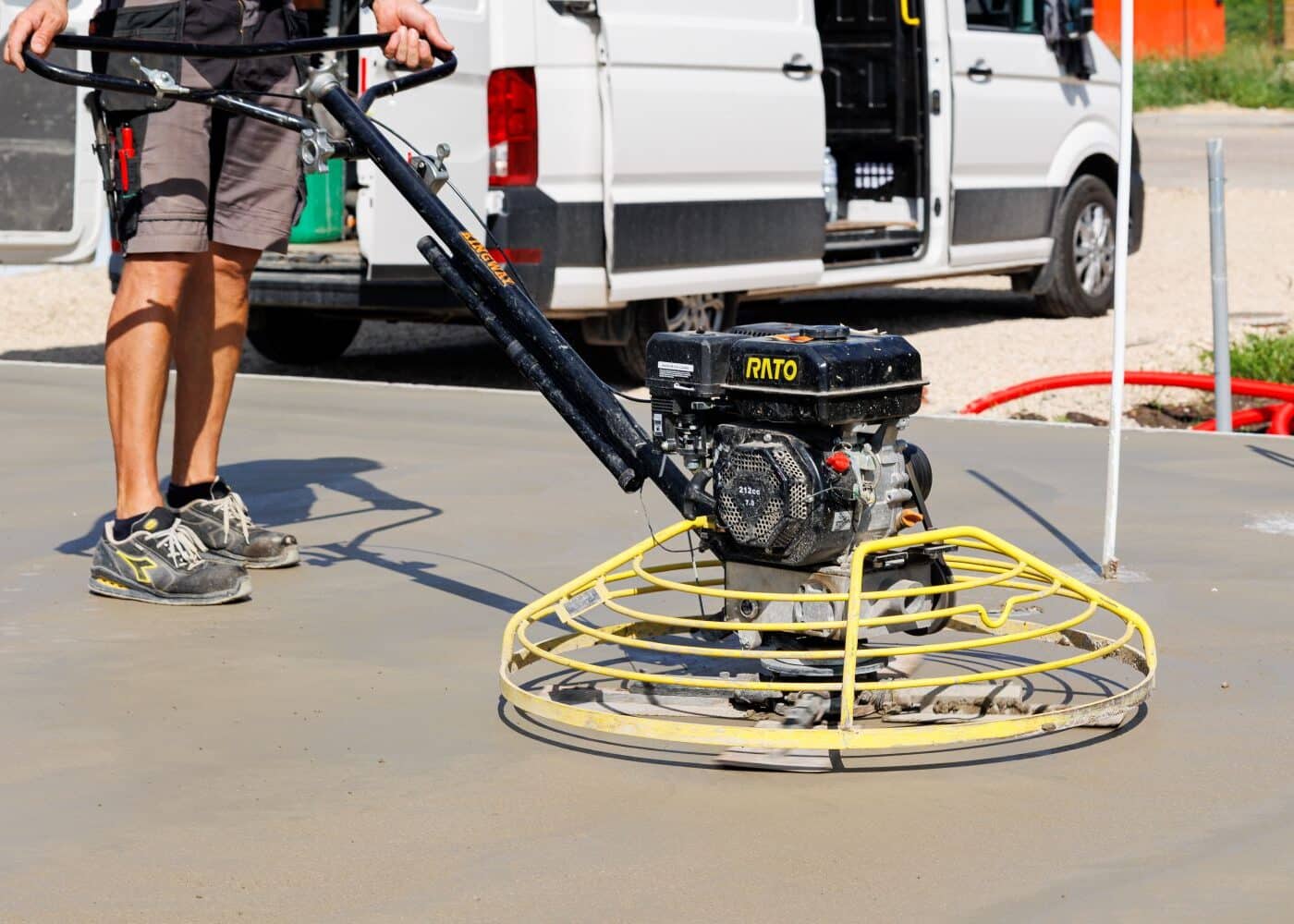 workman using power float on concrete flooring. 