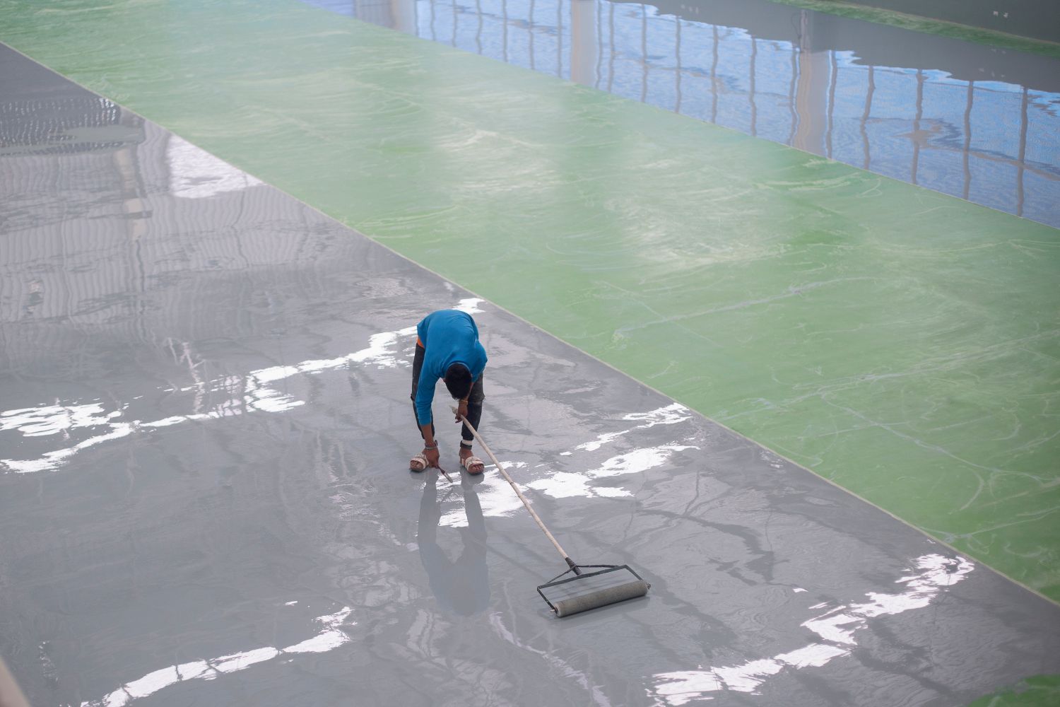 worker pouring resin flooring in warehouse